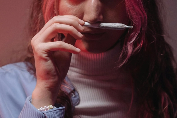 Person smelling a rolled joint, experiencing the aroma of cannabis