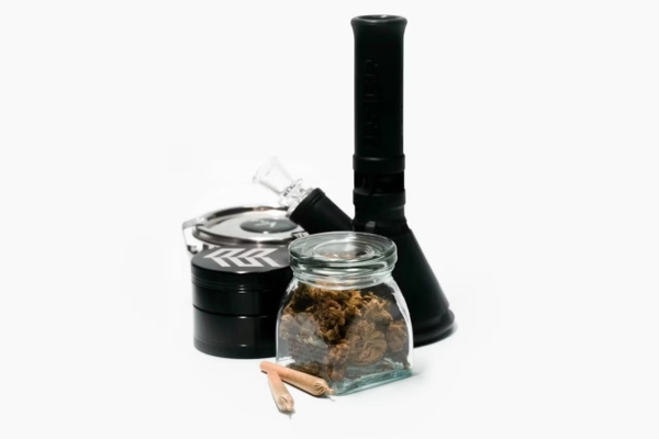 Jar of cannabis buds with grinder and pipe