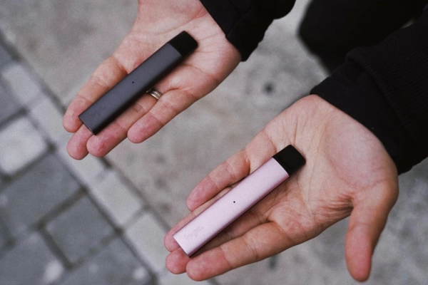 Close-up of a person holding one disposable vape in each hand