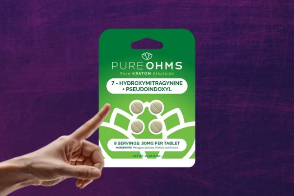 Hand pointing at a packet of Pure OHMS 7-OH tablets