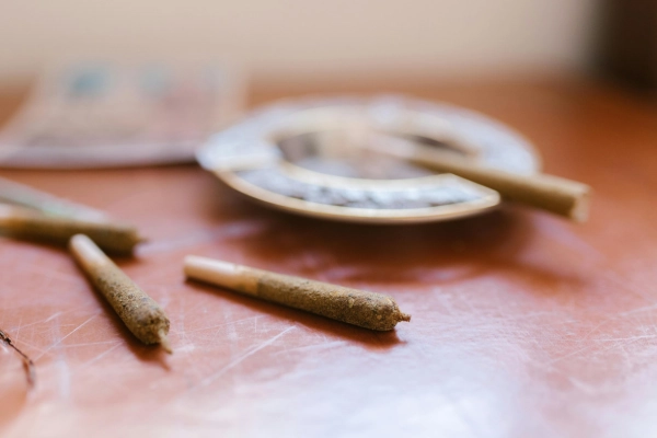 Partially smoked cannabis joints resting on an ashtray on a wooden table