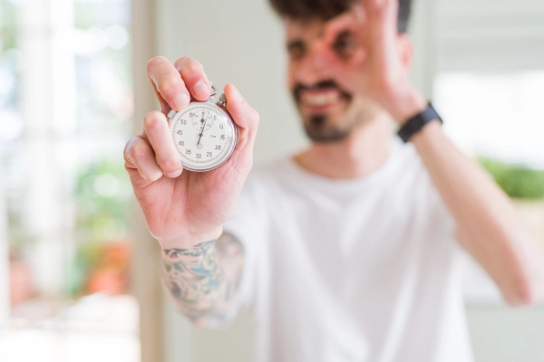 Close-up of a man holding a stopwatch, symbolizing the timing and onset of sugar-free THC edibles