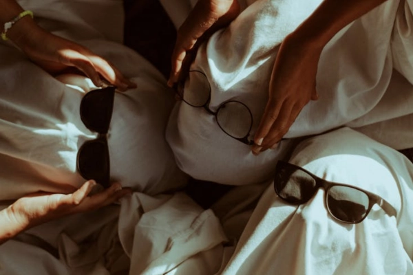 Friends dressed as ghosts wearing sunglasses during a relaxed Cannabis Halloween celebration, playful and cozy atmosphere