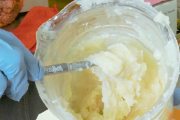 Freshly whipped live badder with a bright color and smooth, uniform texture inside a mixing container