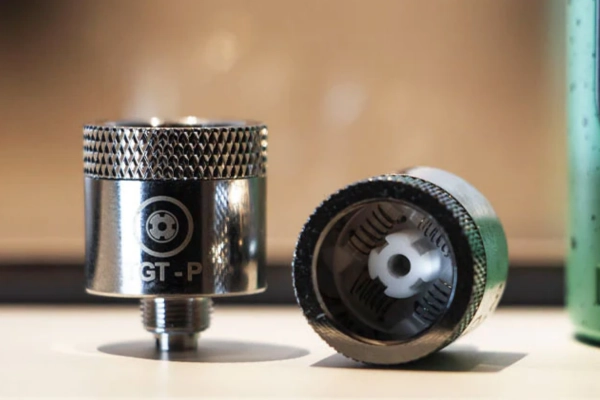 Close-up of two metal vaporizer coils with one showing the internal ceramic heating chamber