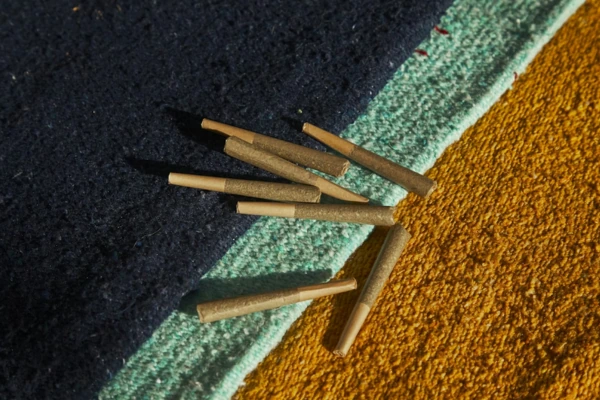 Several pre-rolled joints scattered on a textured floor with blue and yellow tones