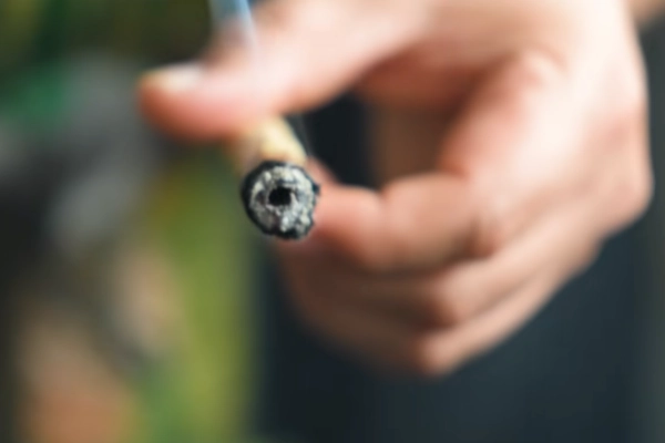 A person holding a lighted hash hole